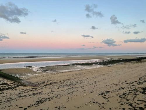 - une vue sur la plage au coucher du soleil dans l'établissement Appartement 2 chambres - 50m de la mer - parking, à Lion-sur-Mer