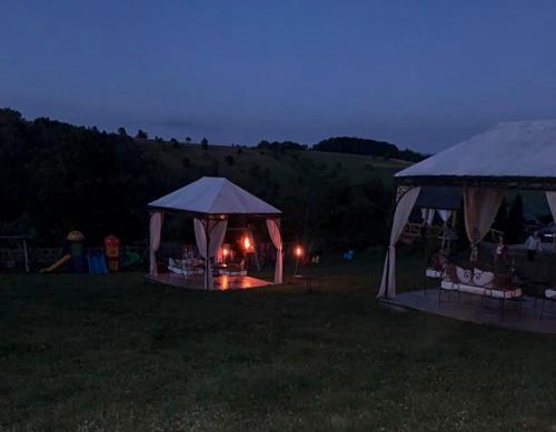 a couple of gazebos in a field at night at Casa Bradet in Întorsura Buzăului