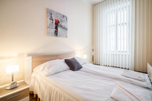 a bedroom with a large white bed and a window at Pyvo Street Home with balcony near the Danube in Budapest