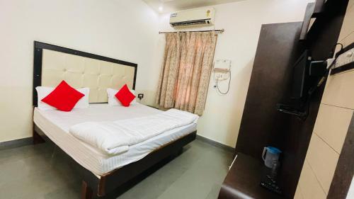 a bedroom with a bed with two red pillows at Hotel Prabhat Palace in Kota