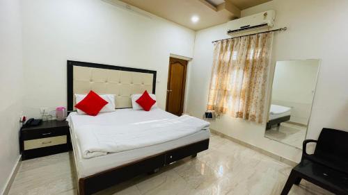 a bedroom with a bed with red pillows and a mirror at Hotel Prabhat Palace in Kota