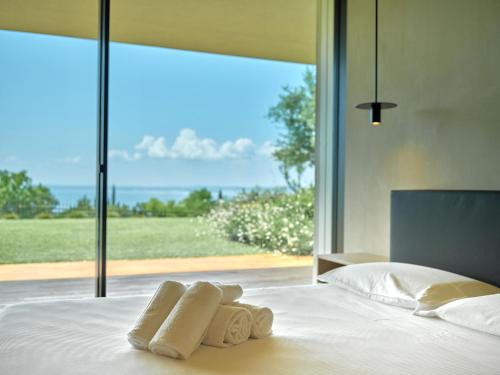 a bed with two towels on it with a large window at VillasGarda - Villa Bardolino in Bardolino