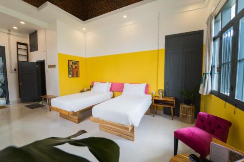 two beds in a room with yellow walls at Baan Pila in Luang Prabang