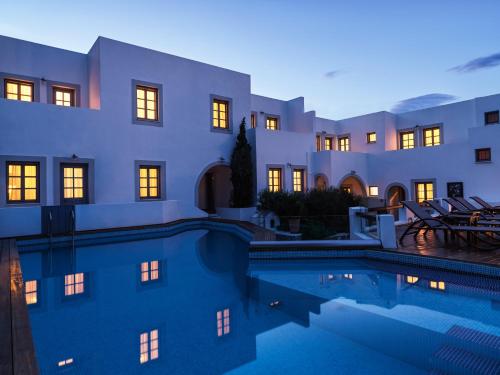 a villa with a swimming pool in front of a building at The Petra, Small Luxury Hotels of the World in Patmos