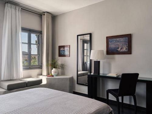 a bedroom with a bed and a desk and a mirror at The Petra, Small Luxury Hotels of the World in Patmos