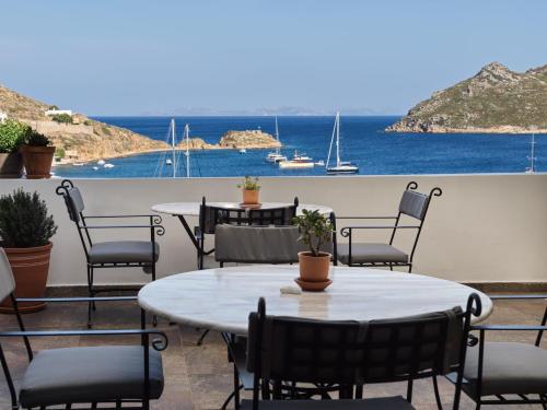 a patio with tables and chairs and a view of the ocean at The Petra, Small Luxury Hotels of the World in Patmos