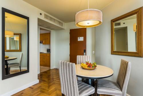 a dining room with a table and chairs and a mirror at Chatrium Sathon Bangkok in Bangkok