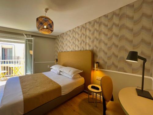 1 dormitorio con 1 cama, 1 mesa y 1 lámpara en Hotel Restaurant Christophe Colomb, en Calvi
