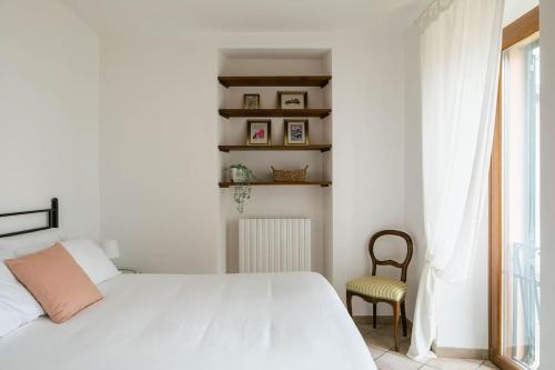 a white bedroom with a bed and a chair at LEONI Apartment Bellagio in Bellagio