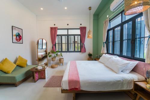 a bedroom with a bed and a couch and windows at Baan Pila in Luang Prabang