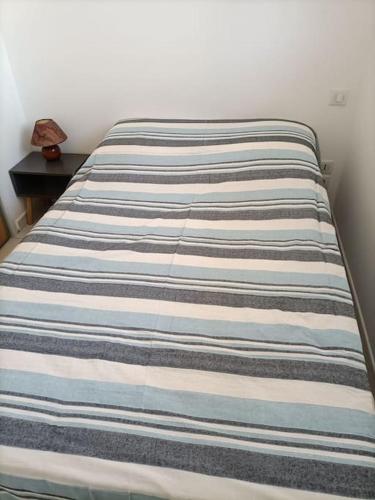 - un lit avec une couverture rayée dans l'établissement Chalet La Mer Veille 2, à Gruissan