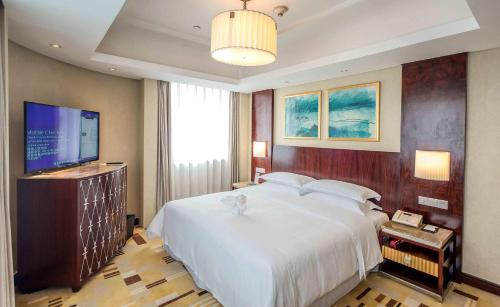 a bedroom with a large bed and a flat screen tv at Sheraton Guiyang Hotel in Guiyang