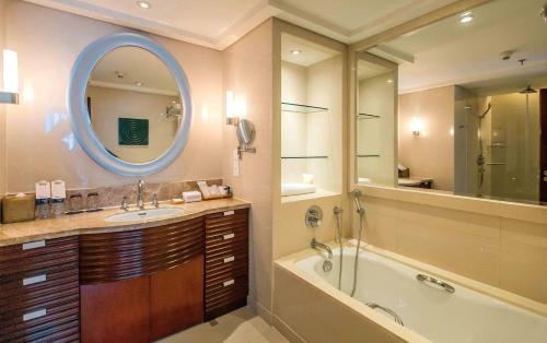 La salle de bains est pourvue d'une baignoire, d'un lavabo et d'un miroir. dans l'établissement Sheraton Guiyang Hotel, à Guiyang