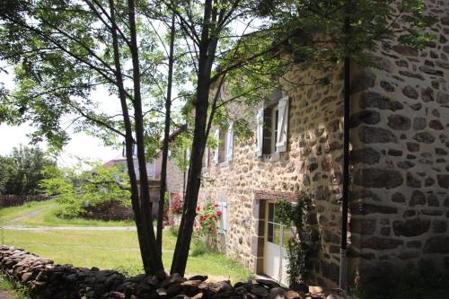 una casa de piedra con árboles delante de ella en Le Relais de Garabit, en Anglards-de-Saint-Flour