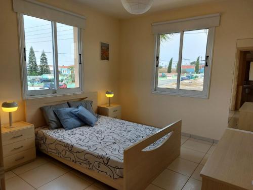 a bedroom with a bed with two windows at Pyla Palms Resorts A2 102 in Pyla