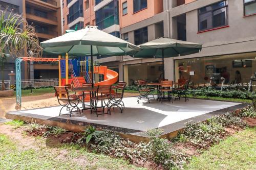 uma mesa e cadeiras com guarda-sóis e um parque infantil em msotsi homes 3 em Nairobi