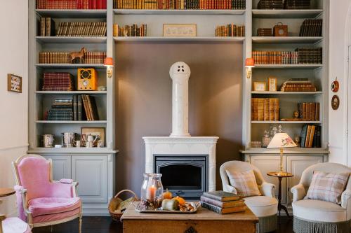 een woonkamer met een open haard en een boekenplank bij La Maison d’Hôtes in Silly