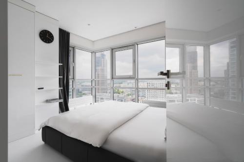 a white bedroom with a bed and a large window at J&K Platinum Towers in Warsaw