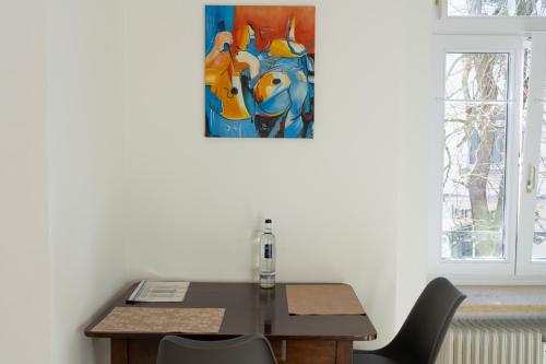 a table and chairs with a painting on the wall at Ferienwohnung Baden Baden in Baden-Baden
