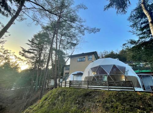 a tent on a hill in front of a house at glampark Morinoyado Nagano in Urugi