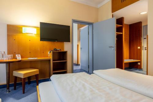 a hotel room with a bed and a desk and a tv at Dresdner Tor Süd in Wilsdruff