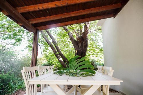 a white table and chairs on a porch with a tree at כפר הנופש קיבוץ גדות Kibbutz Gadot Galilean Resort in Gadot