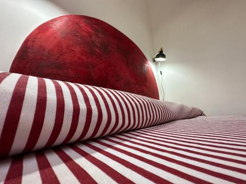 a red and white bed with a red and white striped pillow at Baglio Mazzara in Custonaci