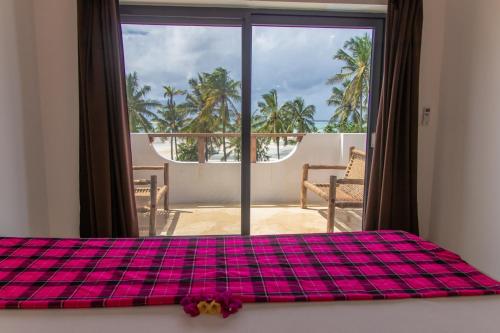 a bedroom with a bed and a view of a balcony at Pingwe Beach Apartments in Pingwe
