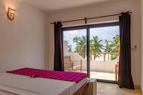 a bedroom with a bed and a large window at Pingwe Beach Apartments in Pingwe