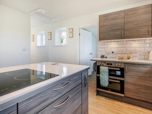a kitchen with wooden cabinets and a counter top at Wheelhouse Cottage in Ullingswick