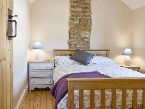 1 dormitorio con 1 cama y 2 mesitas de noche en Corner Cottage en Longstone