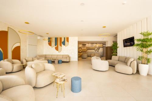 uma grande sala de estar com cadeiras e mesas brancas em Royal Bay Resort - All Inclusive and Free beach accsess em Balchik