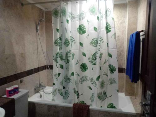 a bathroom with a shower curtain with leaves on it at Kun's Stay Private Apartments in Seminyak