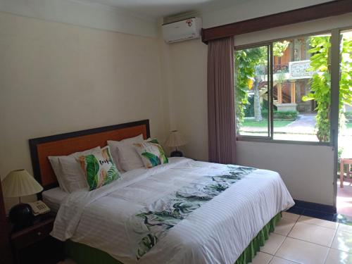 a bedroom with a large bed with a window at Kun's Stay Private Apartments in Seminyak