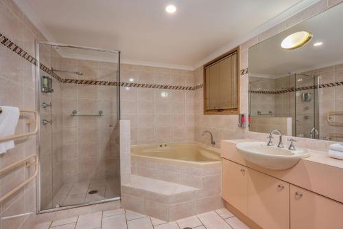 y baño con bañera, lavamanos y ducha. en Lhotsky 2 Bedroom with corner spa bath and central village location, en Thredbo