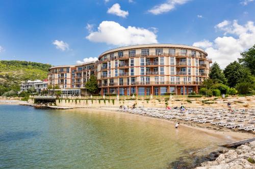 ein Gebäude am Strand mit Stühlen und Wasser in der Unterkunft Royal Bay Resort - All Inclusive and Free beach accsess in Baltschik