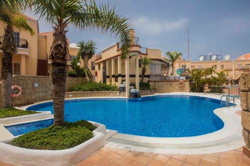 a swimming pool with a palm tree in front of a building at Yucca Park ApartHotel in Adeje