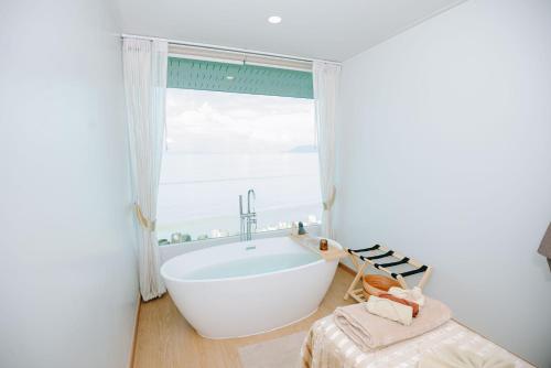 baño con bañera blanca y ventana en Amanda อามันดา, en Ban Pak Ba Ra