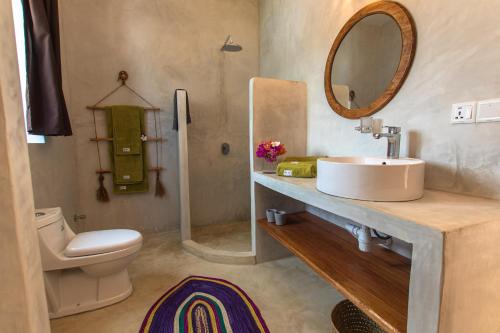a bathroom with a sink and a toilet and a mirror at Pingwe Beach Apartments in Pingwe