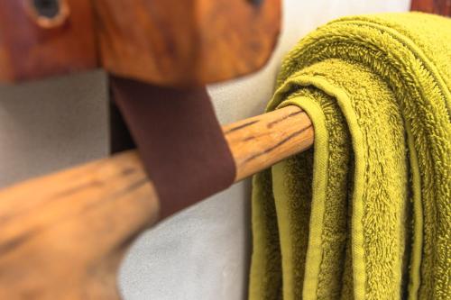 a green towel is hanging on a wooden rack at Pingwe Beach Apartments in Pingwe
