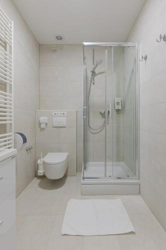 a white bathroom with a shower and a toilet at Stay Swanky Bed & Breakfast in Zagreb