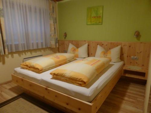 een slaapkamer met een houten bed met 2 kussens bij Haus Anita in Wald am Arlberg