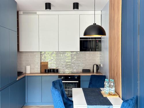 una cocina con armarios azules y una mesa con sillas azules en DMK Blue Apartment near Warsaw-Modlin Airport, en Nowy Dwór Mazowiecki