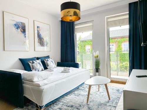 uma sala de estar com um sofá branco e cortinas azuis em DMK Blue Apartment near Warsaw-Modlin Airport em Nowy Dwór Mazowiecki