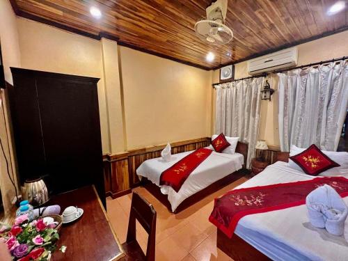 um quarto com duas camas e uma mesa com uma mesa sidx sidx sidx em Nocknoy Lanexang Guest House em Luang Prabang