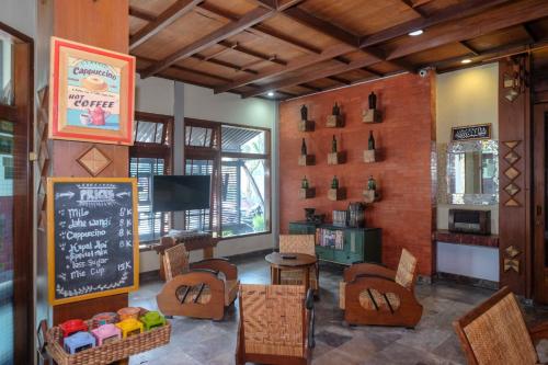 Urbanview Hotel Syariah Wisnugraha by RedDoorz في يوغياكارتا: مطعم مع سبورة على الحائط وطاولة وكراسي