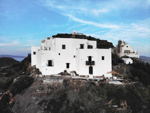 un gran edificio blanco en la cima de una montaña en Castrum Traditional Sunset Suites en Plaka Milou