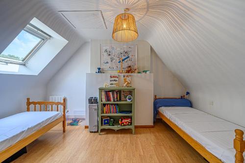 a attic bedroom with two beds and a book shelf at Ty Chaumière - Charmante Petite Chaumière en pierre avec jardin in Theix