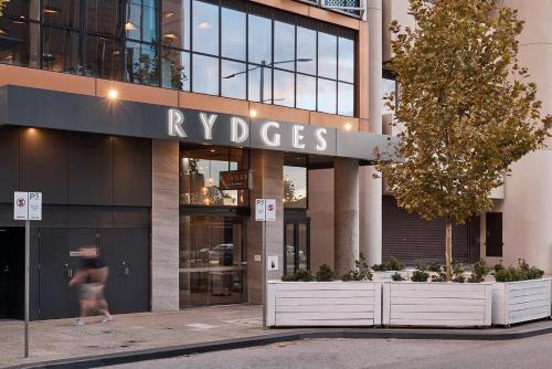 パースにあるRydges Perth Kings Squareの建物前を歩く女