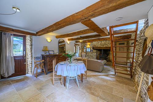 une salle à manger avec une table et une cheminée dans l'établissement Ty Chaumière - Charmante Petite Chaumière en pierre avec jardin, à Theix